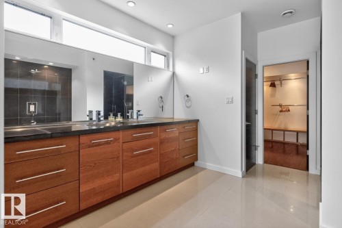 Long wood-finish vanity with dual vessel sinks, dark countertop, and large mirror - 14A Birch Drive, St. Albert, AB 