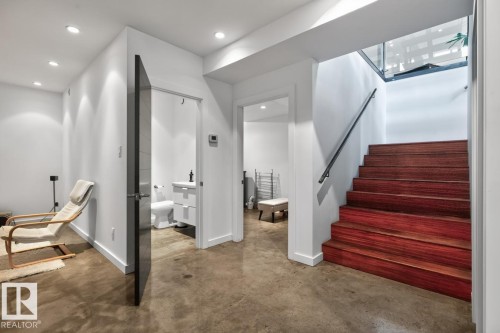 Wood-finish stairs with a dark handrail, complemented by polished concrete flooring - 14A Birch Drive, St. Albert, AB 