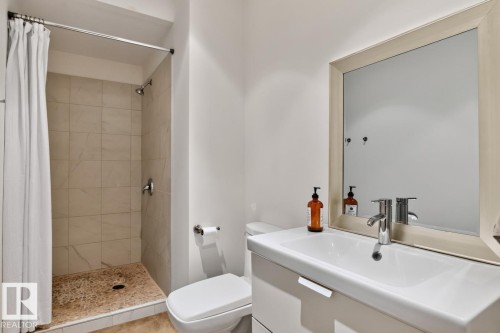 Walk-in shower with natural stone tile, pebble shower floor, and chrome fixtures - 14A Birch Drive, St. Albert, AB 