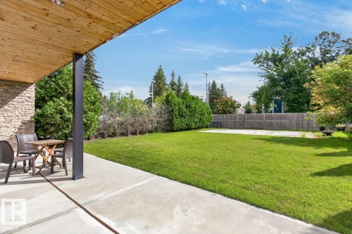 Expansive backyard featuring a manicured lawn, concrete patio, and perimeter fencing - 14A Birch Drive, St. Albert, AB 