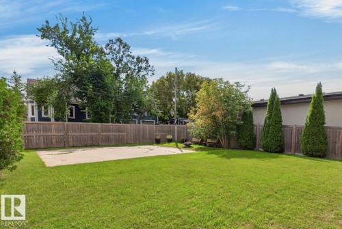 Expansive backyard featuring a large concrete pad, mature trees, and a full privacy fence - 14A Birch Drive, St. Albert, AB 