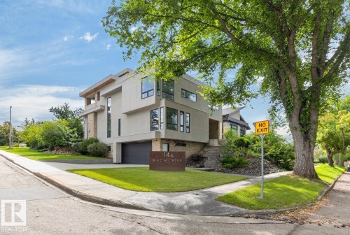 Contemporary architectural design with multiple levels, stone and stucco exterior, large windows, an integrated garage, and a manicured lawn - 14A Birch Drive, St. Albert, AB 