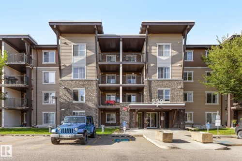 Multi-story building featuring stone and siding exterior, multiple private balconies, and a covered main entrance - #306 530 Watt Bv Sw, Edmonton, AB 