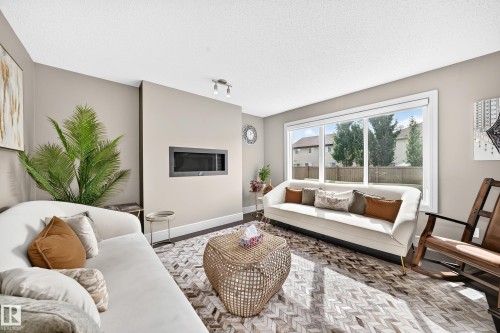 Recessed linear fireplace, dark wood-finish flooring, large picture window, track lighting fixture, and light neutral wall paint - 12035 168 Avenue Nw, Edmonton, AB 