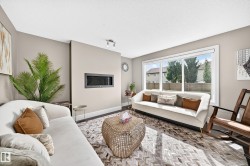 Recessed linear fireplace, dark wood-finish flooring, large picture window, track lighting fixture, and light neutral wall paint - 