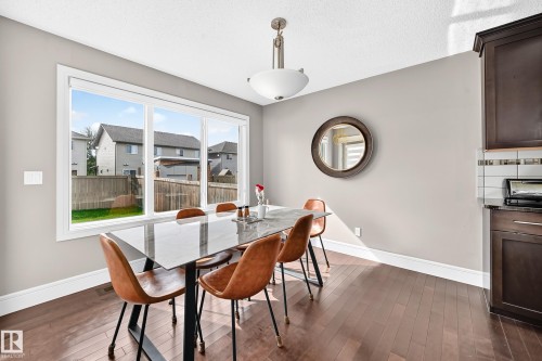 Expansive triple-pane window, wood-finish flooring, dark wood cabinetry, white subway tile backsplash, and a modern ceiling fixture - 12035 168 Avenue Nw, Edmonton, AB 