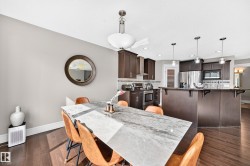 Open-concept kitchen and dining area featuring dark wood-finish cabinetry, stainless steel appliances, a breakfast bar, and wood-finish flooring - 