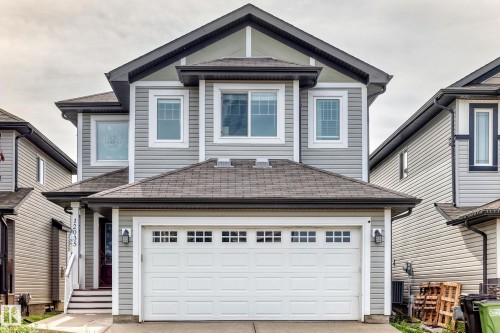 Two-story residence featuring light gray siding, dark gray roof shingles, a white paneled garage door with upper window inserts, and white trim accents - 12035 168 Avenue Nw, Edmonton, AB 