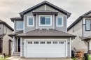 Two-story residence featuring light gray siding, dark gray roof shingles, a white paneled garage door with upper window inserts, and white trim accents - 12035 168 Avenue Nw, Edmonton, AB 