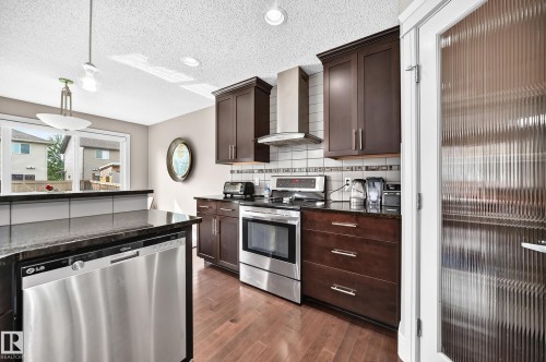 Stainless steel appliances, rich wood-finish cabinetry, solid surface countertops, tile backsplash, and wood-finish flooring - 12035 168 Avenue Nw, Edmonton, AB 