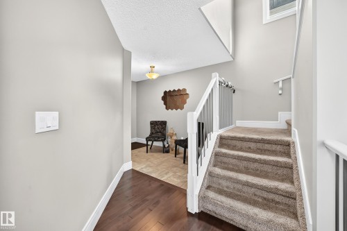 Carpeted staircase with white railing and metal balusters, wood-finish flooring, and a recessed ceiling light fixture - 12035 168 Avenue Nw, Edmonton, AB 