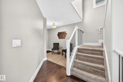 Carpeted staircase with white railing and metal balusters, wood-finish flooring, and a recessed ceiling light fixture - 