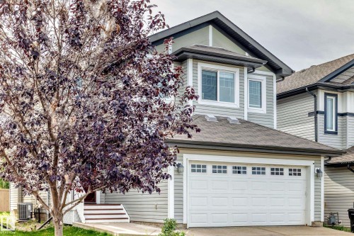 Two-story exterior with light gray siding, white trim accents, attached front-facing garage, and covered front entry - 12035 168 Avenue Nw, Edmonton, AB 