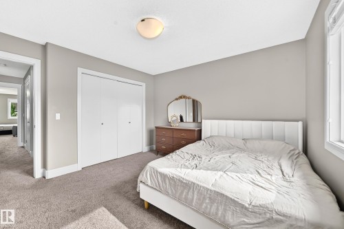 Neutral tone wall paint, light-colored carpeting, large window, flush-mount ceiling light, white bi-fold closet doors - 12035 168 Avenue Nw, Edmonton, AB 