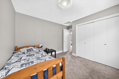 Neutral gray wall paint, textured ceiling, carpeted flooring, white bi-fold closet doors, and a ceiling-mounted light fixture - 12035 168 Avenue Nw, Edmonton, AB 
