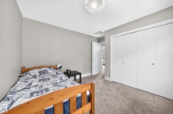 Neutral gray wall paint, textured ceiling, carpeted flooring, white bi-fold closet doors, and a ceiling-mounted light fixture - 