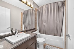 Bathroom featuring a vanity with an integrated rectangular sink, dark granite-style countertop, and a built-in bathtub with shower - 