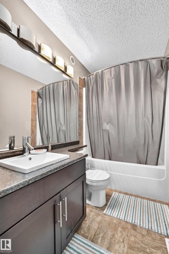Dark wood-finish vanity with a white rectangular sink, dark speckled countertop, and chrome faucet - 12035 168 Avenue Nw, Edmonton, AB 