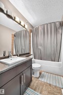 Dark wood-finish vanity with a white rectangular sink, dark speckled countertop, and chrome faucet - 
