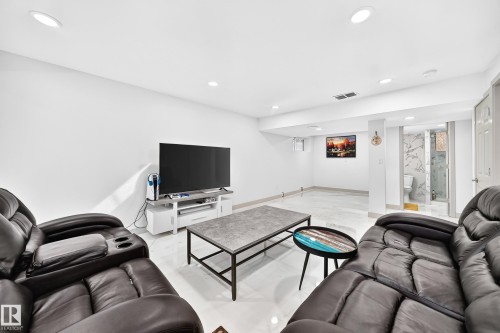Recessed lighting, light-toned tile flooring, and a visible bathroom featuring a glass-enclosed shower and marble-look wall tiling - 12035 168 Avenue Nw, Edmonton, AB 
