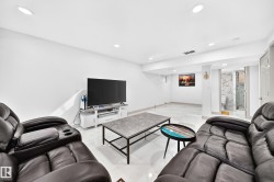 Recessed lighting, light-toned tile flooring, and a visible bathroom featuring a glass-enclosed shower and marble-look wall tiling - 