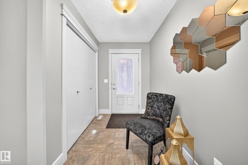 Entryway featuring tile flooring, a solid core entry door with decorative glass, and a flush mount ceiling light - 12035 168 Avenue Nw, Edmonton, AB 
