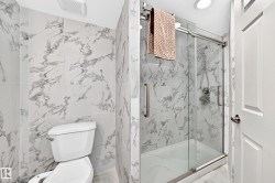 Tiled shower with sliding glass door, recessed lighting, and a white toilet - 