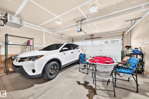 Attached two-car garage featuring a concrete floor, overhead lighting, and an automatic garage door opener - 12035 168 Avenue Nw, Edmonton, AB 