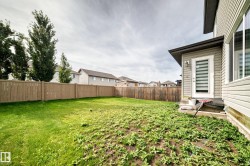 Expansive backyard featuring a wood privacy fence, mature trees, and a ground-level exterior door - 