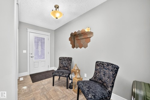 Entryway featuring tile flooring, a white paneled door with decorative glass, and a semi-flush mount ceiling light - 12035 168 Avenue Nw, Edmonton, AB 