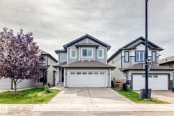 Two-story exterior with light gray siding, dark trim accents, double garage door, concrete driveway, and front lawn - 