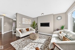 Spacious living area featuring rich wood-finish flooring, a contemporary built-in fireplace, and large windows with natural light - 