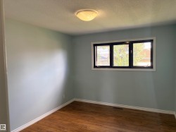 Wood-finish flooring with white trim, light blue wall paint, and a multi-pane window with dark framing bedroom 3 upstairs - 