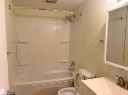 White bath and shower combination with a curved shower curtain rod, basement bathroom. - 