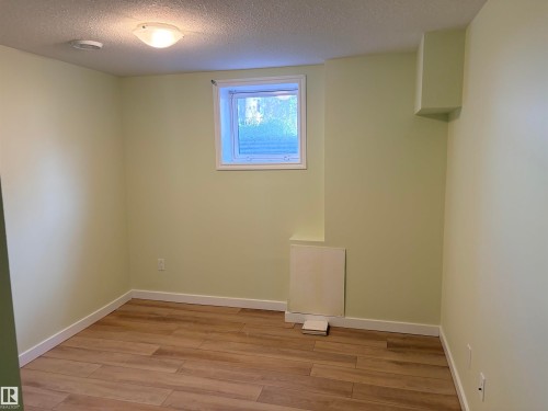 Recessed window, wood-finish flooring, flush mount ceiling light, light-toned wall paint, white trim basement bedroom - 13219 107 Street Nw, Edmonton, AB 