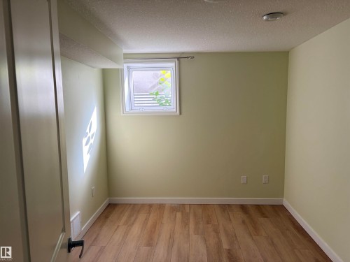Wood-finish flooring with white trim, a single window, and a flush-mount ceiling light Basement - 13219 107 Street Nw, Edmonton, AB 