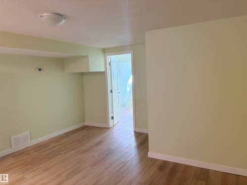 Wood-finish flooring, light-toned walls, white trim, and a flush-mount ceiling light Basement - 13219 107 Street Nw, Edmonton, AB 