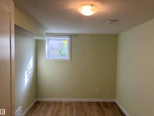 Wood-finish flooring with white trim and light-toned walls Basement - 13219 107 Street Nw, Edmonton, AB 