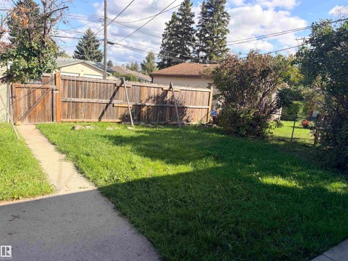 Private fenced backyard with a concrete pathway and mature perimeter landscaping - 13219 107 Street Nw, Edmonton, AB 