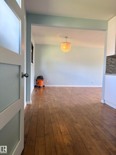 Hardwood-style flooring throughout, an open doorway, and an overhead decorative light fixture - 13219 107 Street Nw, Edmonton, AB 
