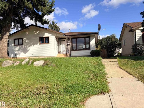 White siding exterior with a brown shingle roof, dark-framed windows, and an established front yard - 13219 107 Street Nw, Edmonton, AB 