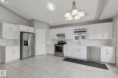 White shaker-style cabinetry, stainless steel appliances, tile flooring, recessed lighting, and a decorative chandelier - 16807 78 Street Nw, Edmonton, AB 
