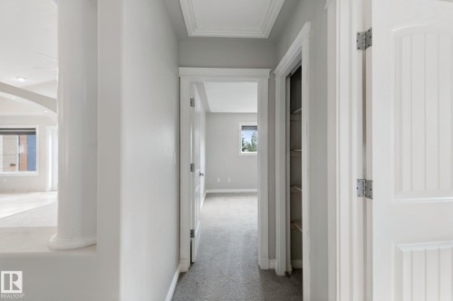Hallway with carpet flooring, white paneled doors, and a built-in linen closet - 16807 78 Street Nw, Edmonton, AB 