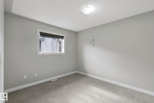 Neutral gray wall paint with white trim, carpeting, a single window with blinds, and an overhead flush-mount light fixture - 16807 78 Street Nw, Edmonton, AB 