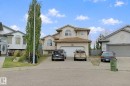 Two-story residence featuring a neutral stucco exterior, a two-car attached garage, arched windows, and a concrete driveway - 16807 78 Street Nw, Edmonton, AB 