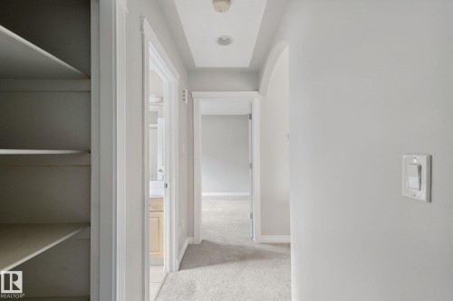 Hallway featuring recessed lighting, tray ceiling, built-in shelving, and neutral wall tones - 16807 78 Street Nw, Edmonton, AB 
