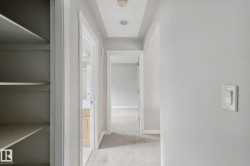 Hallway featuring recessed lighting, tray ceiling, built-in shelving, and neutral wall tones - 