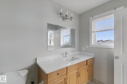 Wood-finish vanity with an integrated sink, polished chrome faucet, and a large mirror - 16807 78 Street Nw, Edmonton, AB 