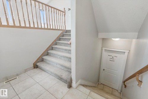 Staircase featuring carpeted treads, a light wood railing, and an upper landing with two windows - 16807 78 Street Nw, Edmonton, AB 