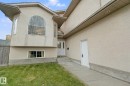 Stucco exterior with a prominent arched window, white entry door, and a concrete walkway - 16807 78 Street Nw, Edmonton, AB 